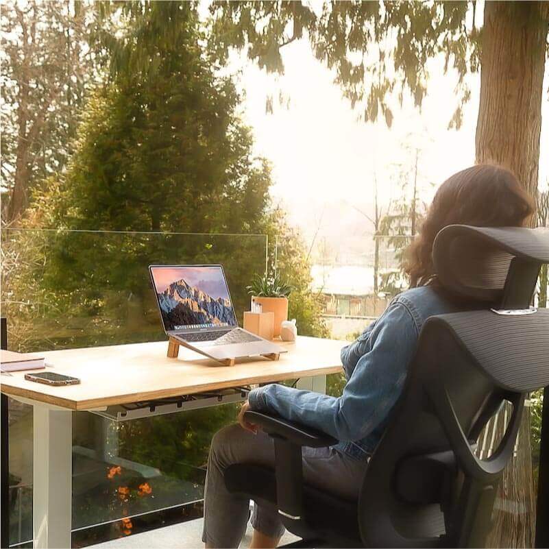 A woman setting on an office workstation surrounded by a natural view