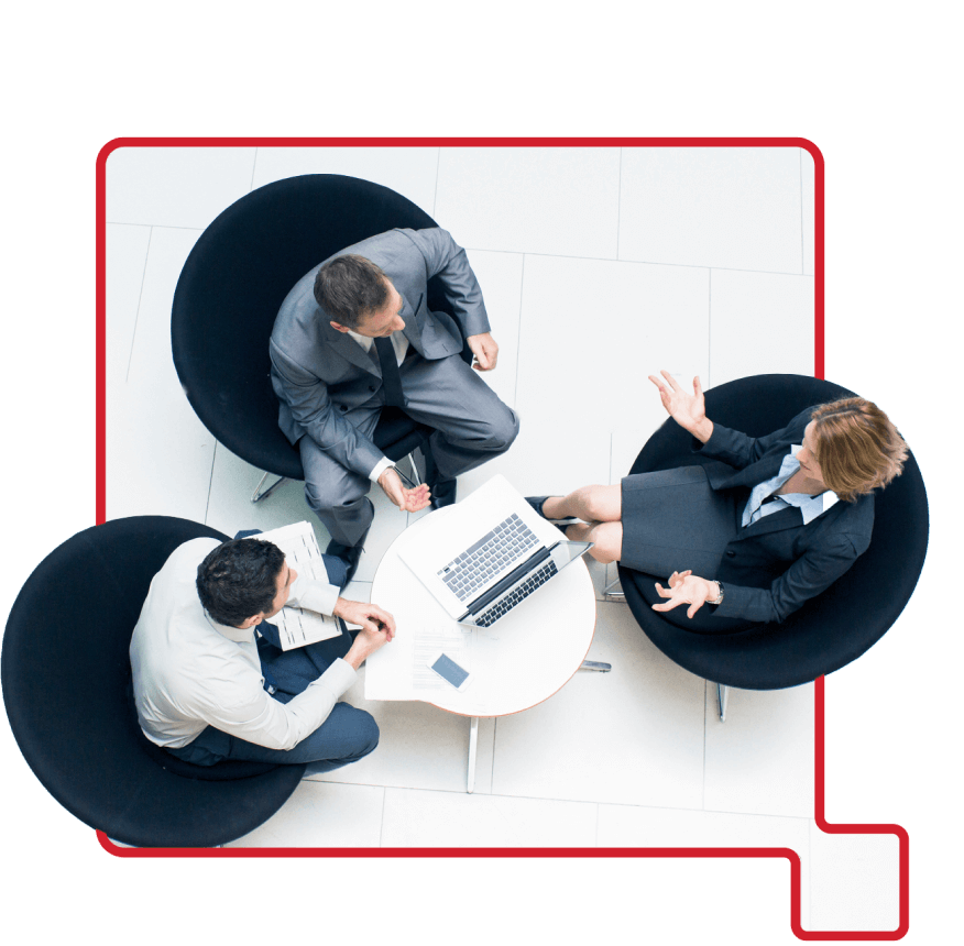 Overhead view of three professionals in a meeting seated around a round table with a laptop and documents.
