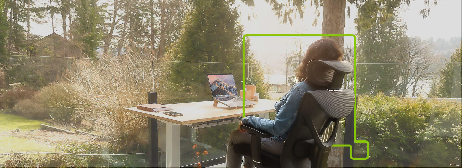 A woman setting on an office workstation surrounded by a natural view